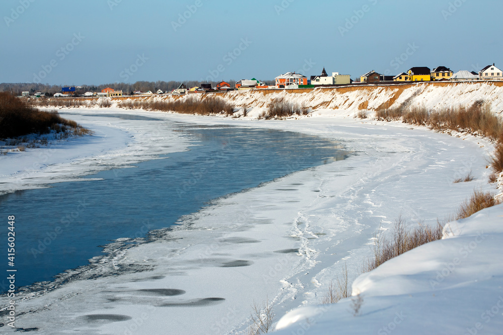 Houses on the edge of a ravine where the river flows in winter. Winter landscape. Fantastic view