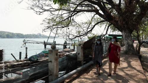 Indian Mother and daughter walking along the sea shore in Fort Kochi beach on summer vacation Kerala India 4K slow motion video footage. outing  in coastal region walkway. photo