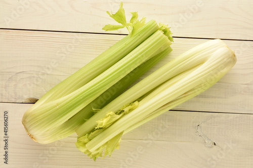Two light green natural, juicy stalks of celery on a wooden table, close-up, top view.