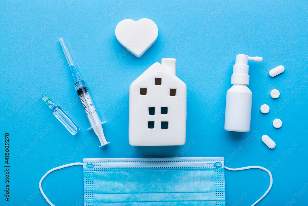 Injection with house figure on a blue background as a concept of staying at home if you feel sick. Home treatment with a prescription from the doctor to recover from coronavirus. 