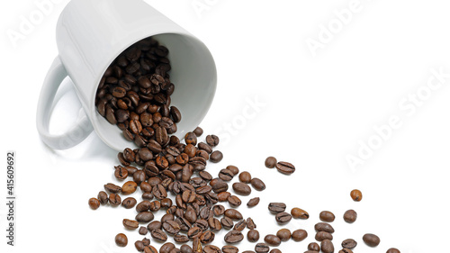 Roasted coffee beans fall from a lying coffee cup isolated on white background