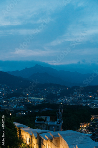 View of on top of Seoul city wall at dusk with city and mountain behind.
