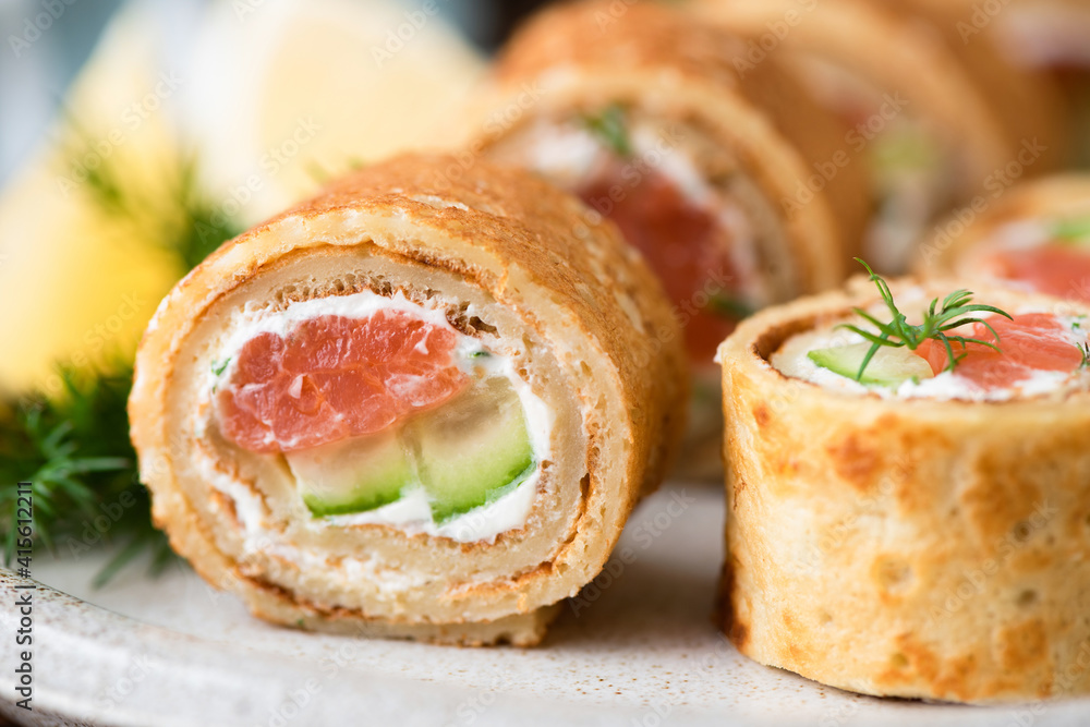 Appetizer crepe rolls with smoked salmon and cucumber closeup view