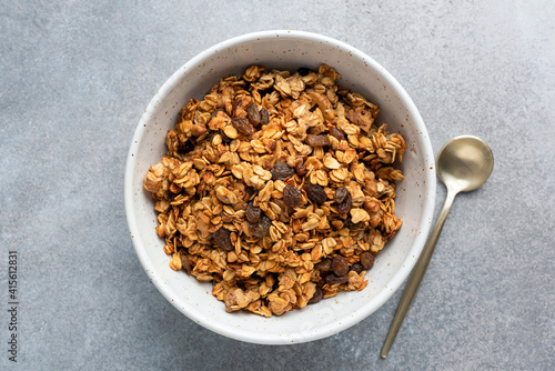 Homemade oat raisin granola in bowl on grey concrete background, top view. Healthy breakfast cereals