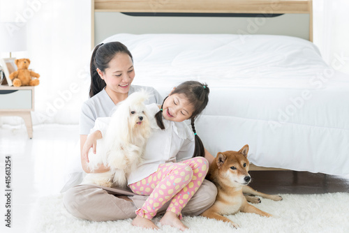 A mother whose daughter was playing with a white-haired maltese and had a Shiba Inu by her bed.