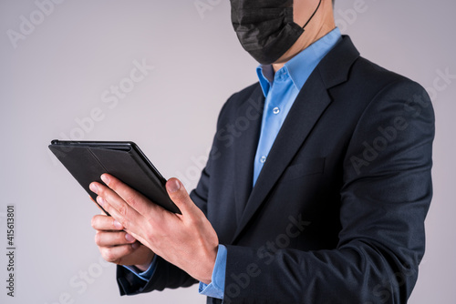 Office worker with tablet in protective mask on gray background