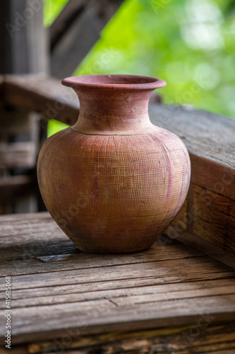 Old clay vase of manual work on wooden table in thai home