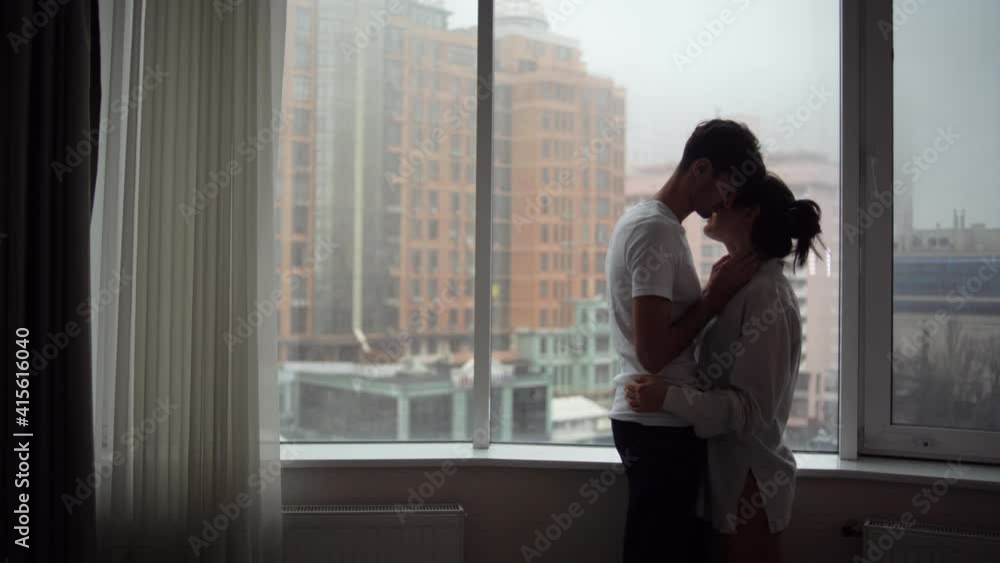 Enamored man and woman of Caucasian ethnicity at the window, kiss. Concept of love. Enamored man and woman of Caucasian ethnicity at the window, kiss. Concept of love.