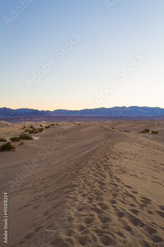 Footprints in sand dunes in Death Valley National Park at sunrise.