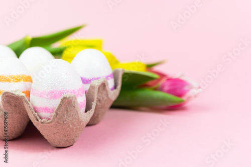 Easter painted eggs with tulips on a pink background. Copy space. Easter celebration concept.