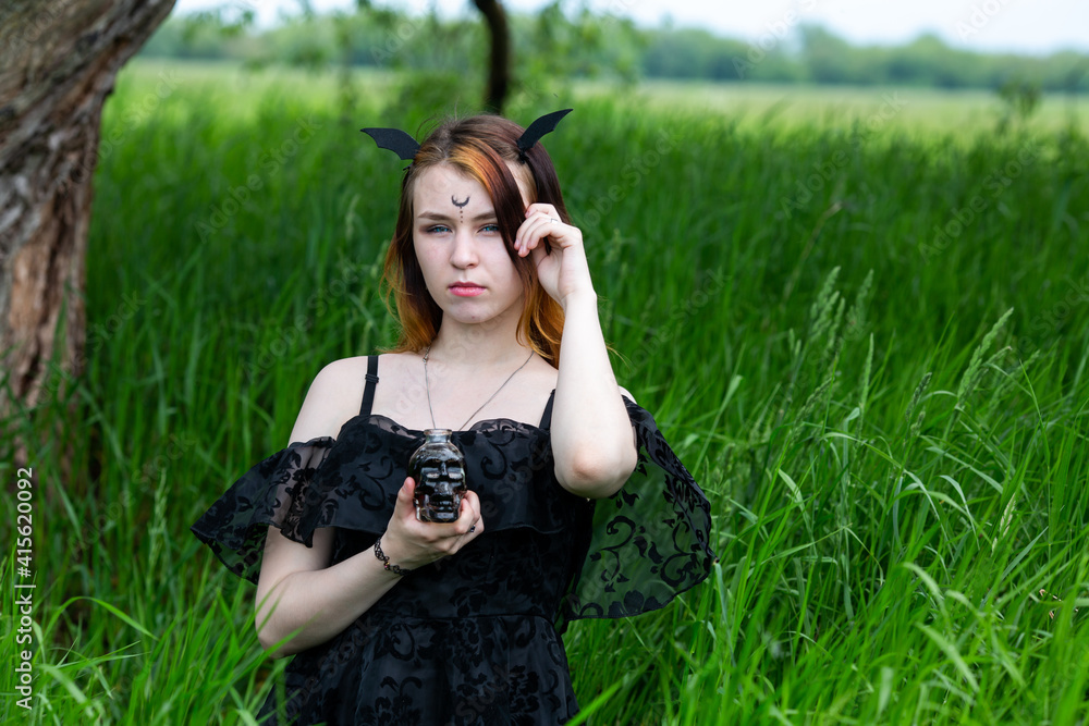 Young beautiful sorceress conducts a ceremony in a green forest on a summer day. Modern witchcraft.