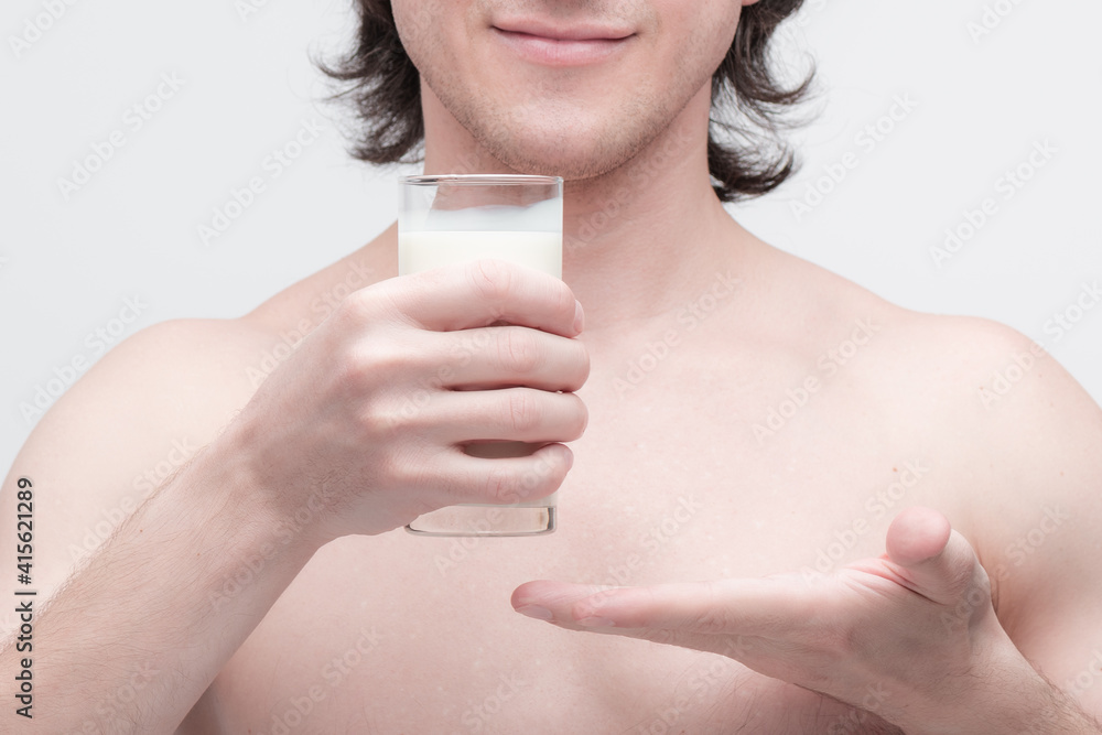 Kind man holding glass of milk and showing on it with a palm. closeup photo Kind man holding glass of milk and showing on it with a palm. closeup photo
