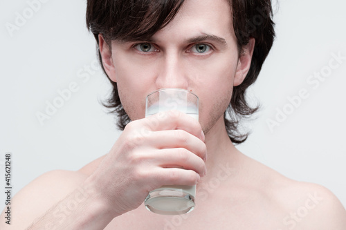 Closeup photo of handsome young caucasian man drinking milk from a glass.