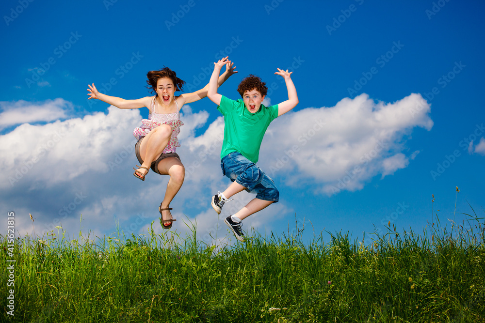 Girl and boy running, jumping against blue sky
Girl and boy running, jumping against blue sky