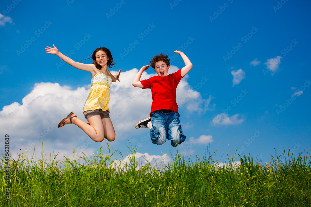 Girl and boy running, jumping against blue sky
Girl and boy running, jumping against blue sky