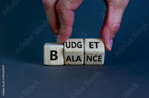 Budget or balance symbol. Businessman turns wooden cubes and changes the word 'balance' to 'budget'. Beautiful grey background, copy space. Business, budget or balance concept.