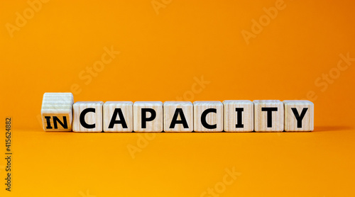 Capacity or incapacity symbol. Turned a wooden cube and changed the word 'incapacity' to 'capacity'. Beautiful orange background. Business and capacity or incapacity concept. Copy space.