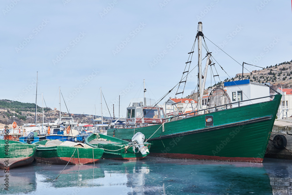 small fishing ship and several boats are moored in the harbor
