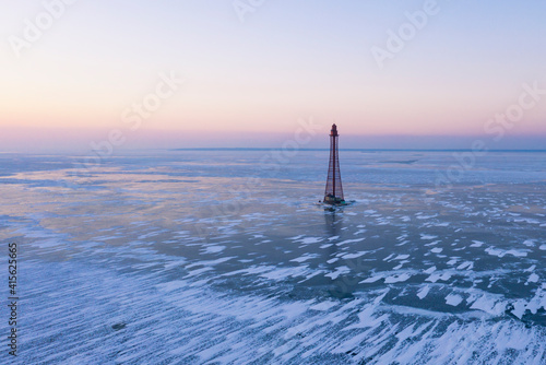 Aerial view of lighthouse frozen in ice at twilight. Drone photo