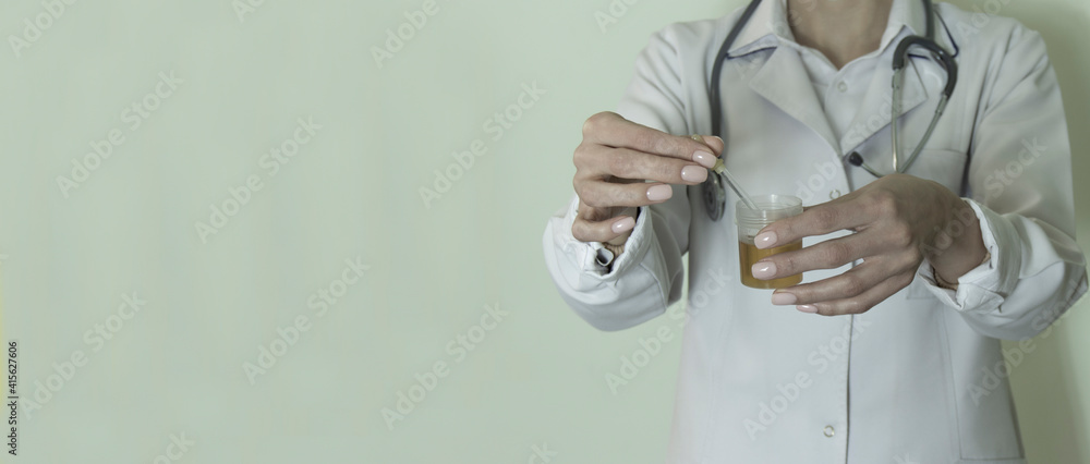 A doctor, lab technician in  holding urine sample in a plastic container, urinalysis and filling the pipette with urine for testing, medical check-up concept.