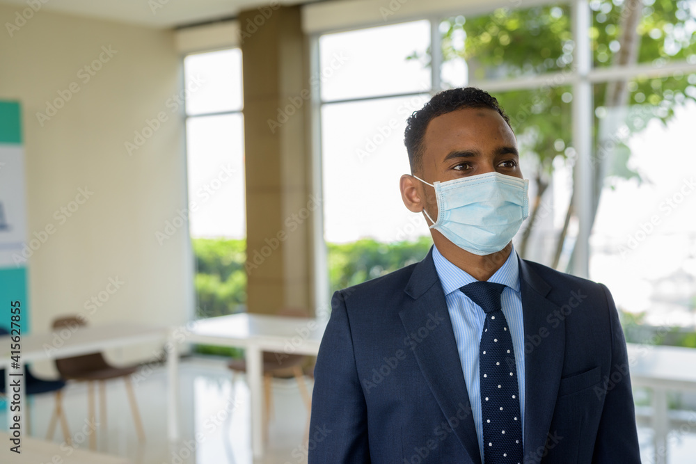 African businessman with surgical medical mask for protection thinking at office African businessman with surgical medical mask for protection thinking at office