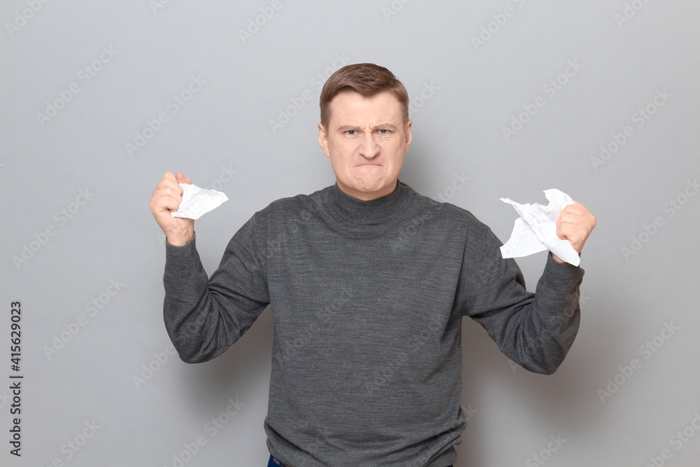 Portrait of angry furious man holding crumpled pieces of torn paper Portrait of angry furious man holding crumpled pieces of torn paper