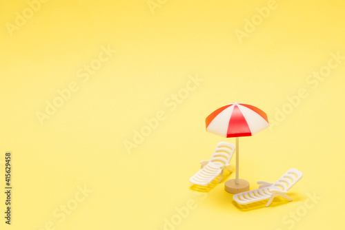 Two sun loungers and a red umbrella on a yellow background. © Nikolay