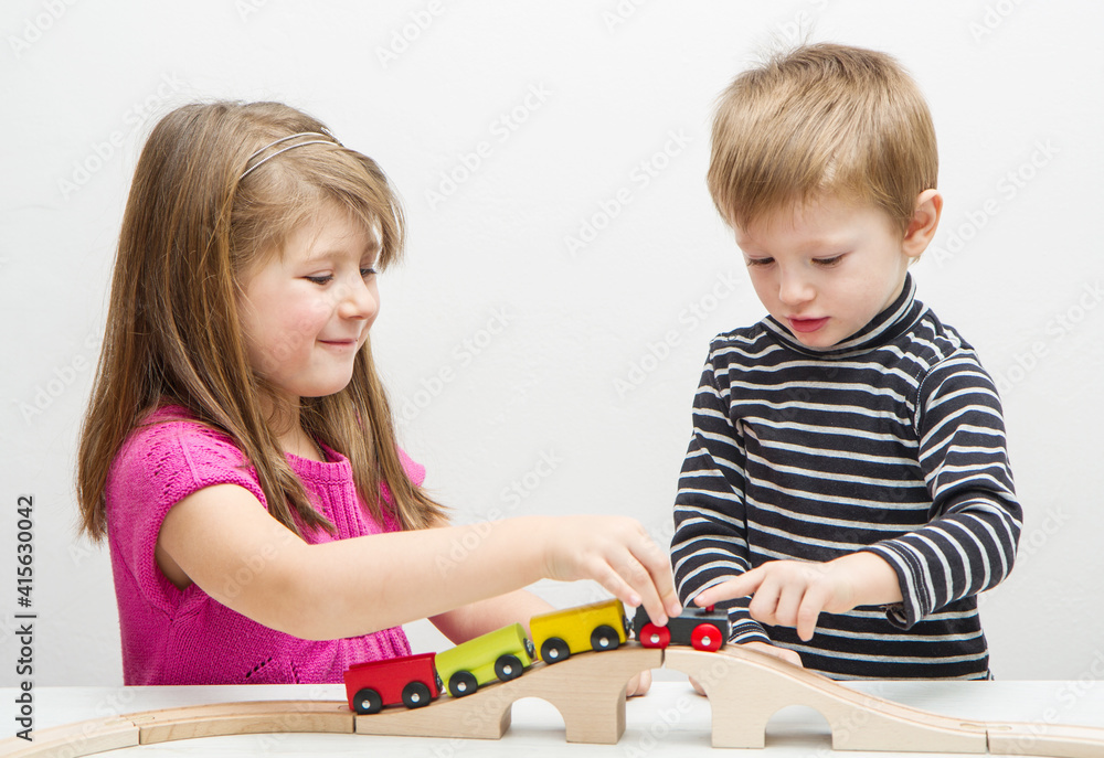 Brother and sister playing with wooden train Brother and sister playing with wooden train