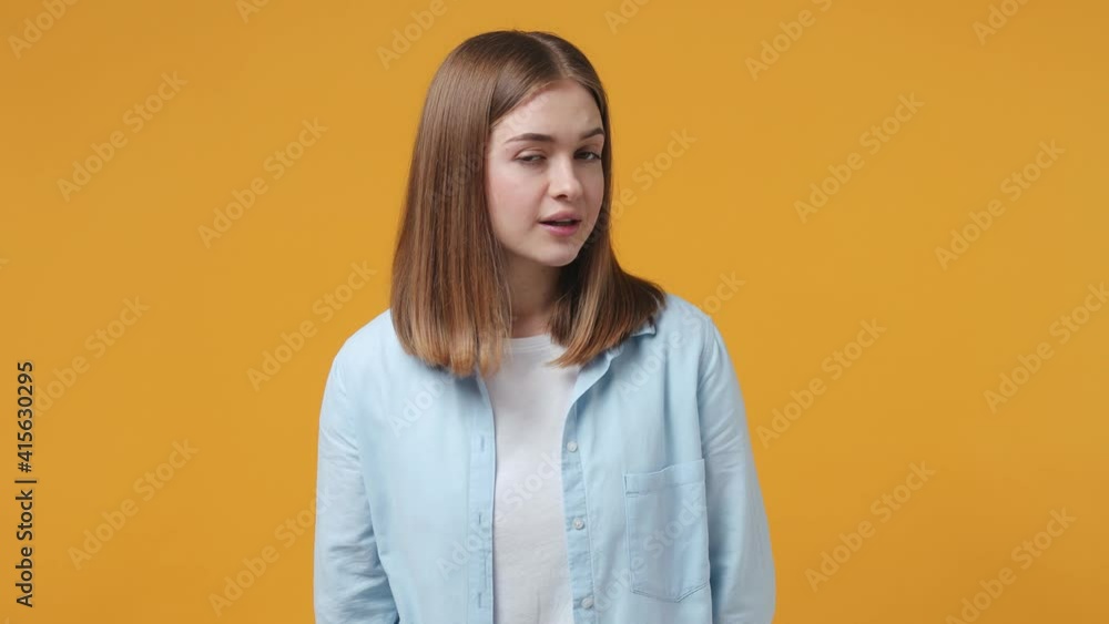 Secret blonde young woman 20s in casual blue shirt posing isolated on yellow color background in studio. People lifestyle concept. Looking aside saying hush be quiet with finger on lips shhh gesture Secret blonde young woman 20s in casual blue shirt posing isolated on yellow color background in studio. People lifestyle concept. Looking aside saying hush be quiet with finger on lips shhh gesture