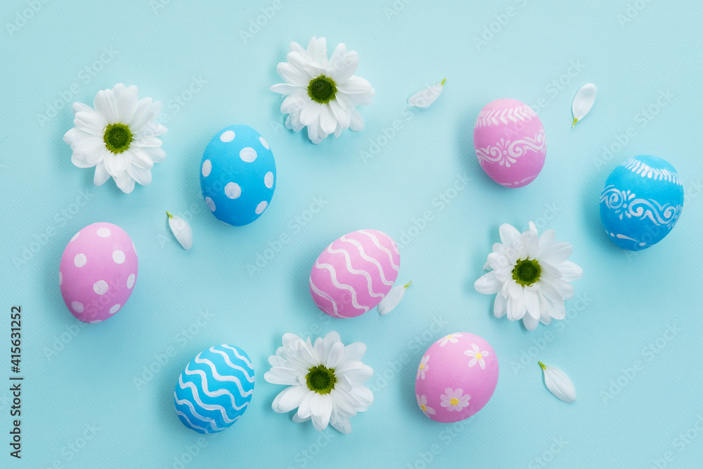 Easter decoration. Festive composition. Spring ornament. Creative arrangement of painted pink blue eggs white daisy flowers petals isolated on light pastel background.