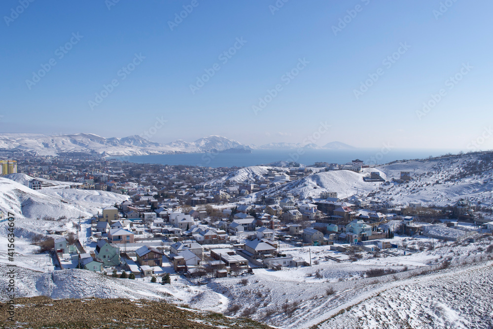 View from the mountain to the snow-covered village of Koktebel in the Crimea and the sea.