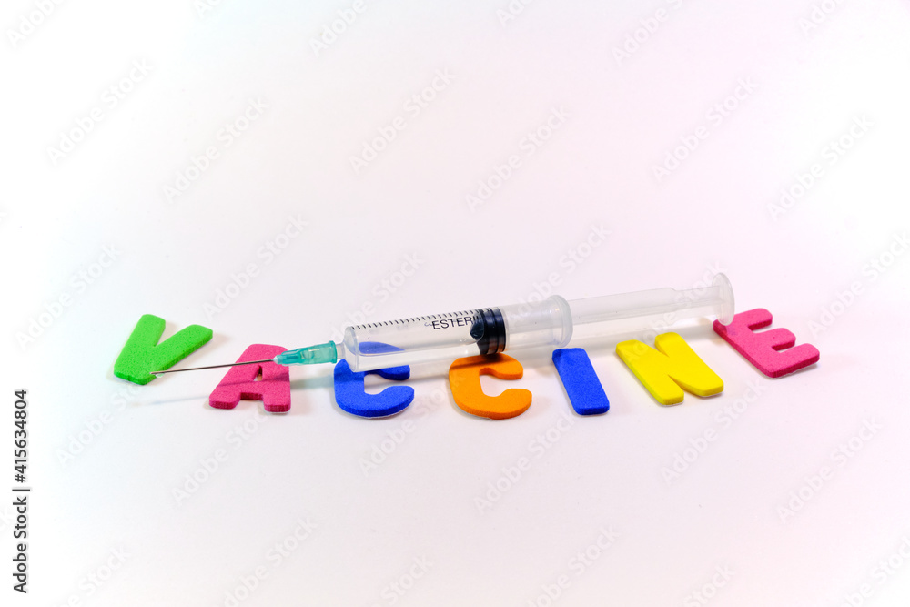 Syringe on a white background and with the word vaccine with colored letters. Syringe on a white background and with the word vaccine with colored letters.