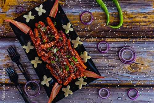 honey chilli potatoes in a spicy sauce, sesame seeds and green onions close-up on a plate on the table. top view