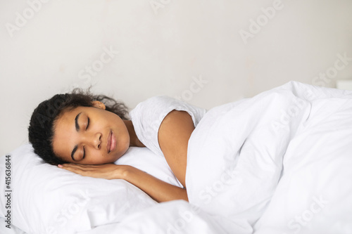 Peaceful girl sleeping well in cozy pure bed in the hotel on soft fresh pillow white linen mattress, enjoy sleep, side view, watching the dreams, dressed in white T-shirt, excellent service