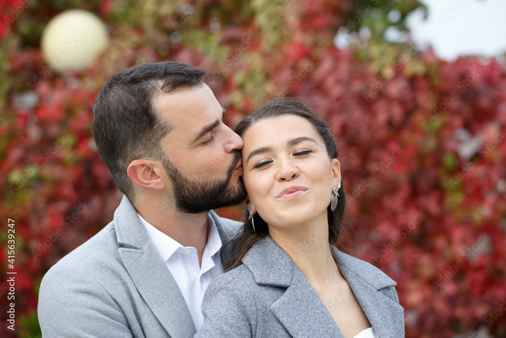 Stylish couple in gray coats gently hugging on the background of autumn leaves. Happy sensual wedding couple embracing. Romantic moments of newlyweds. Stylish couple in gray coats gently hugging on the background of autumn leaves. Happy sensual wedding couple embracing. Romantic moments of newlyweds.