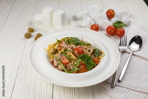 Pasta with herbs and tomatoes on a white wooden table 