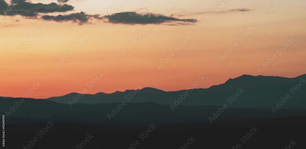 Atardecer en la Sierra de Guadarrama en Madrid, España. Cielo anaranjado con los últimos rayos del sol resaltando la silueta de las montañas ubicadas al norte de Madrid.