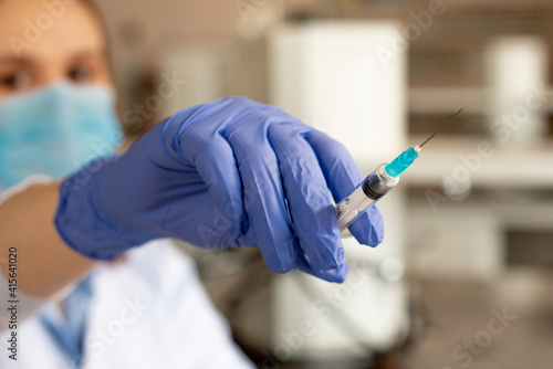 The doctor holds a syringe in blue gloves before vaccination or injection. Coronavirus concept