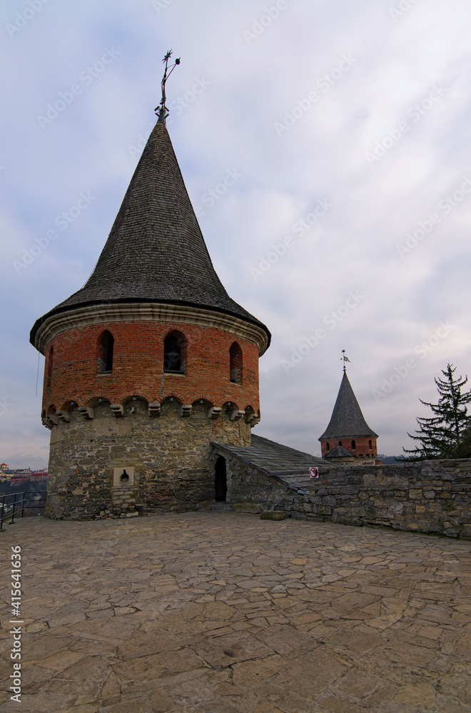 Panoramic view of big stone towers with tile roof against cloudy sky in Kamianets-Podilskyi  fortess. Major tourist attraction in Kamianets-Podilskyi, Ukraine