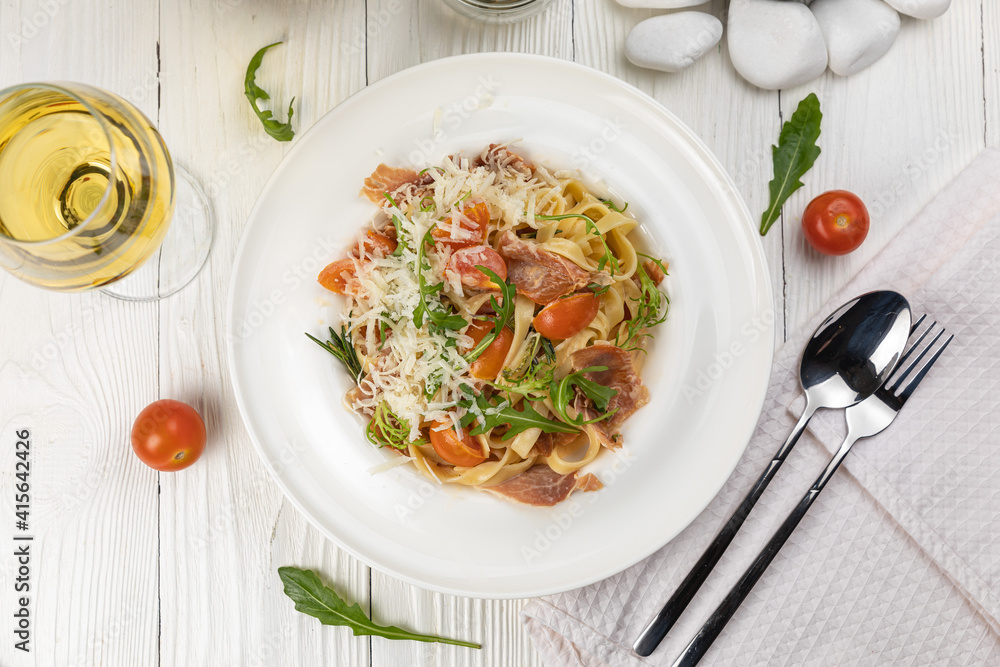 Pasta with herbs and tomatoes on a white wooden table
Pasta with herbs and tomatoes on a white wooden table