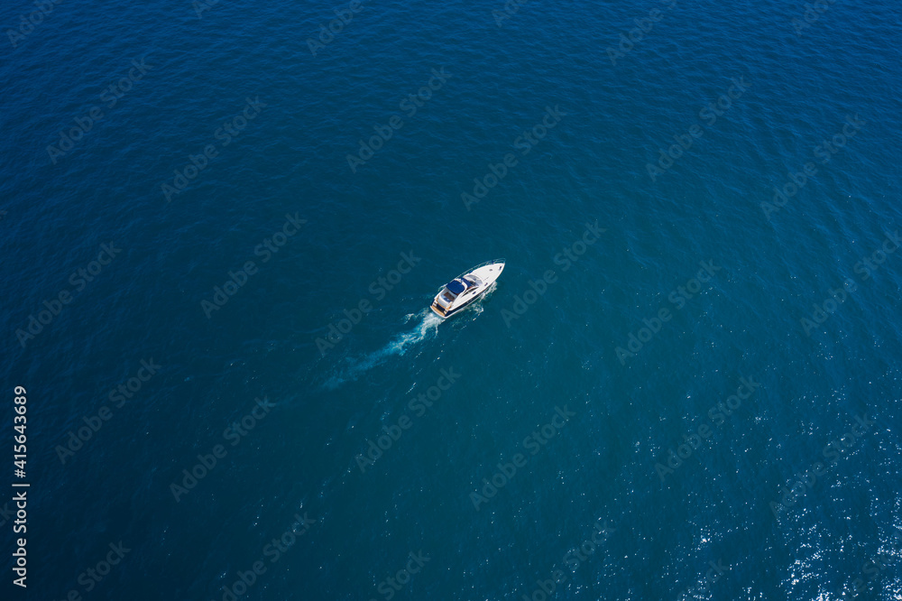 Lonely boat on blue water. White yacht slow motion on blue water, boat top view. Boat in the sun.