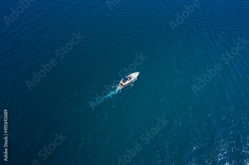 Lonely boat on blue water. White yacht slow motion on blue water, boat top view. Boat in the sun. © Berg