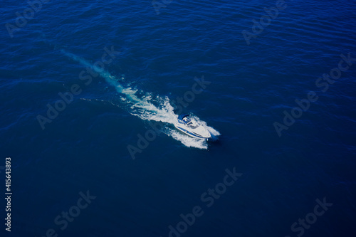 Large white boat on blue water, fast movement, aerial view of the boat