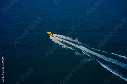 Wallpaper Mural A large yellow boat is moving fast on blue water. Drone view of a boat sailing across the blue clear waters. Top view of a white yacht sailing in the blue sea. Aerial view luxury motor boat. Torontodigital.ca