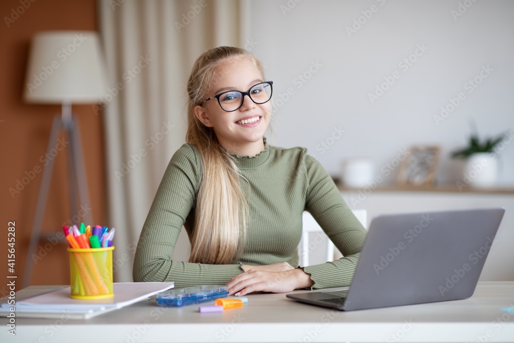 Happy girl sitting at desk with laptop, studying from home Happy girl sitting at desk with laptop, studying from home