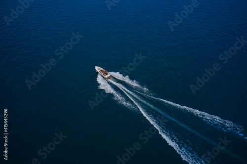 Top view of the boat. Aerial view luxury motor boat. Top view of a white boat sailing in the blue sea. The yacht is moving fast on blue water.