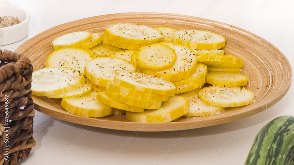 Zucchini slices with garlic seasoning and black pepper closeup on wooden plate on white background Zucchini slices with garlic seasoning and black pepper closeup on wooden plate on white background