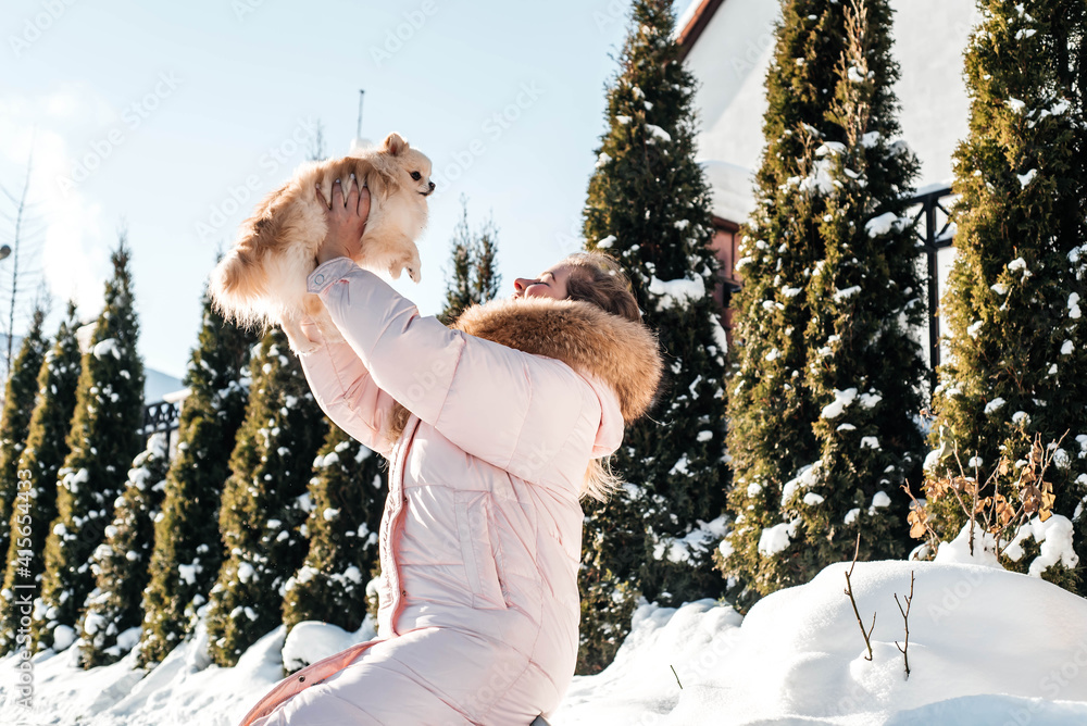 girl with a dog puppy spitz playing in winter outdoors fun girl with a dog puppy spitz playing in winter outdoors fun