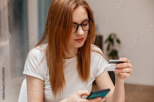 Using smartphone and credit card online shopping. Woman using mobile phone app playing game, shopping online, ordering delivery relax on sofa. A Woman shopping Online On Smartphone With A Debit Card.