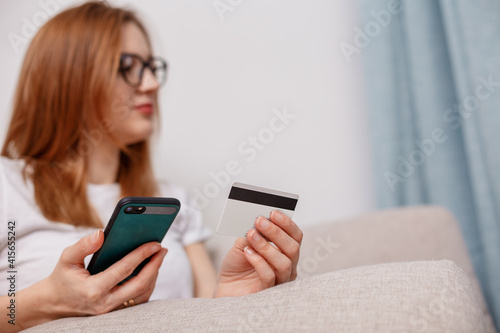 Using smartphone and credit card online shopping. Woman using mobile phone app playing game, shopping online, ordering delivery relax on sofa. A Woman shopping Online On Smartphone With A Debit Card.